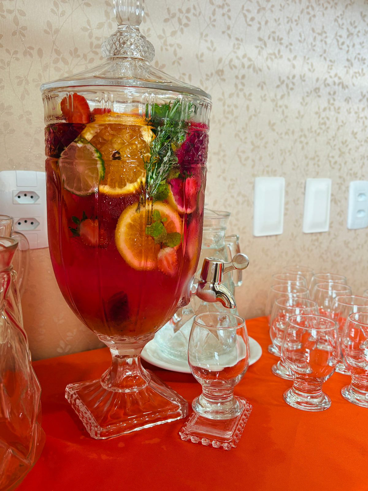 Suqueira de cristal com infusão de frutas, taças prontas para servir